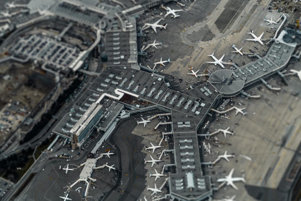 Drohnenaufnahme eines Flughafens, man sieht den gesamten Flugverkehr wie in einer Miniaturaufnahme.